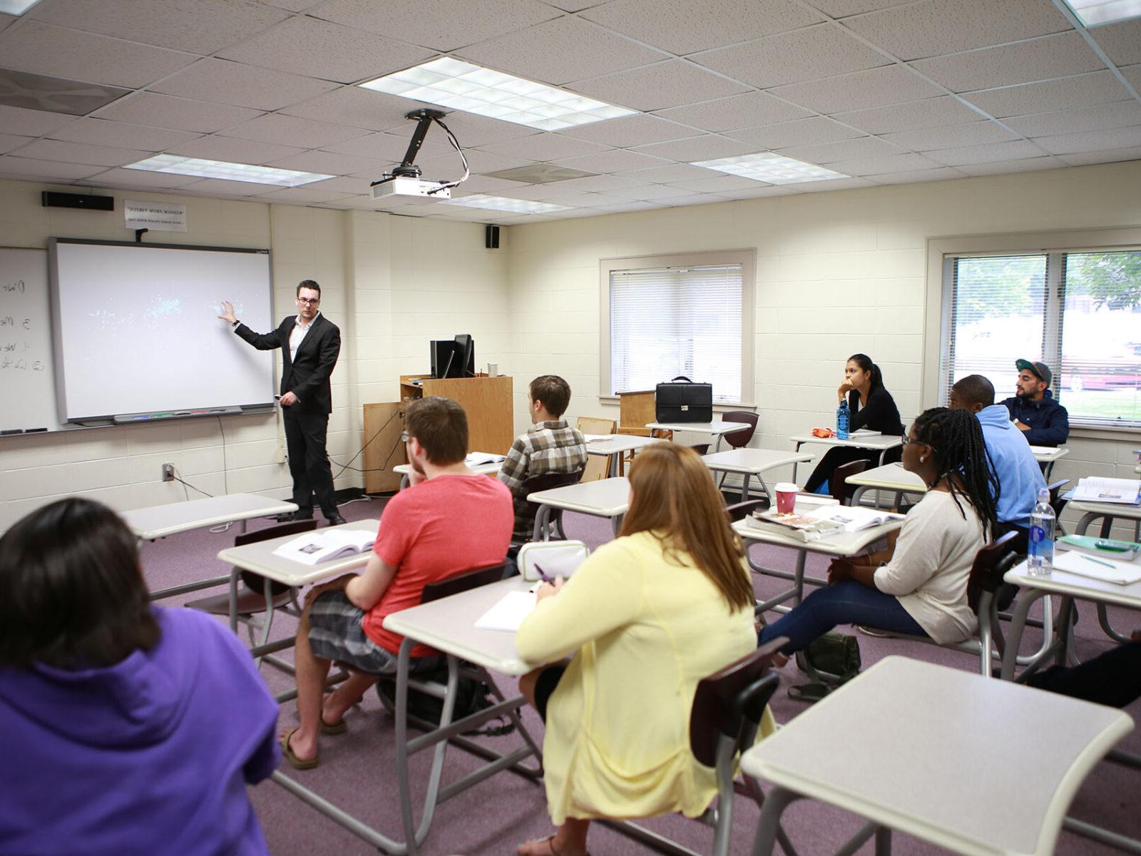 a person standing in front of a classroom with students