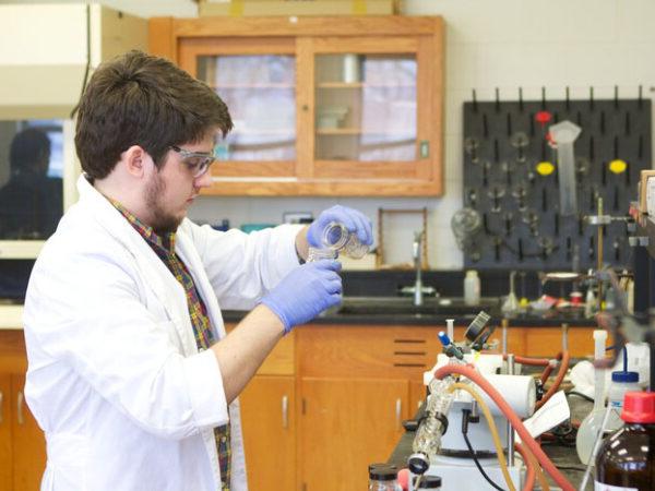 a man wearing gloves and a white coat working in a laboratory